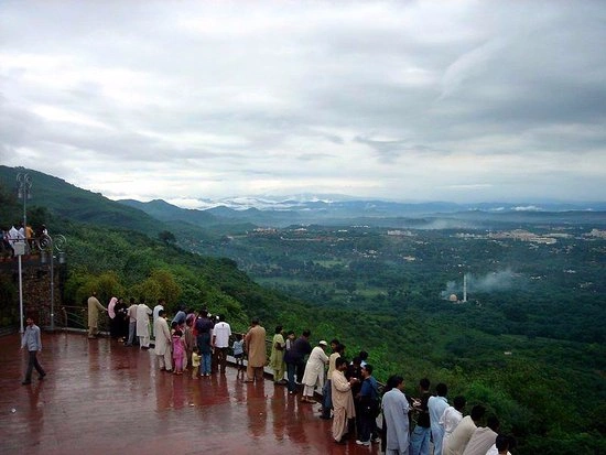 Visitors enjoying a scenic viewpoint overlooking Islamabad’s lush green hills and city landscape under cloudy skies, popular among travelers in 2026.